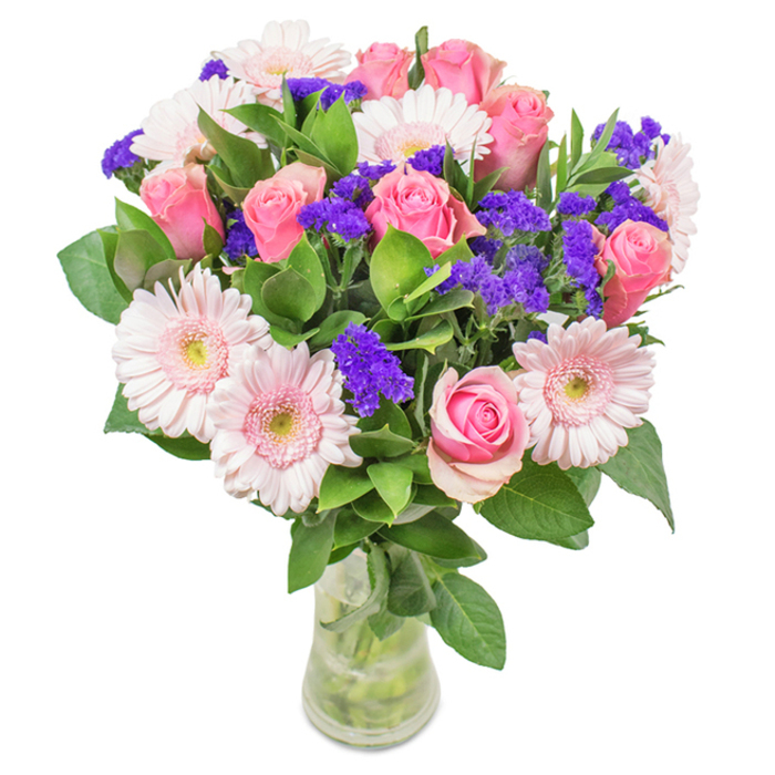 A striking floral arrangement, expertly crafted in Bracknell and displayed in a simple glass vase against a clean white backdrop. This locally inspired bouquet features seven to nine lush pink roses, some tightly furled and others unfolding in graceful spirals, each a symbol of affection and timeless elegance. Nestled among them are five to seven pale pink gerbera daisies, their large, daisy-like faces and soft centres catching the light like blooms after a gentle rain on the grounds of South Hill Park. Purple statice, vivid and textured, offers bold contrast and a touch of wild beauty, weaving through the ensemble in lively clusters. Deep green foliage forms a generous, abundant base, its freshness mirrored in the foliage-trimmed paths of nearby Westmorland Park, bringing a local Bracknell touch. Carefully arranged with visible stems submerged in water, the bouquet suggests recent gathering and expert handling by a Bracknell florist who knows the joy of a perfect bloom. Suitable for birthdays, anniversaries, or as a brightening gift for any home or office, this arrangement expresses joy, celebration, and heartfelt connection to Bracknell's vibrant community.